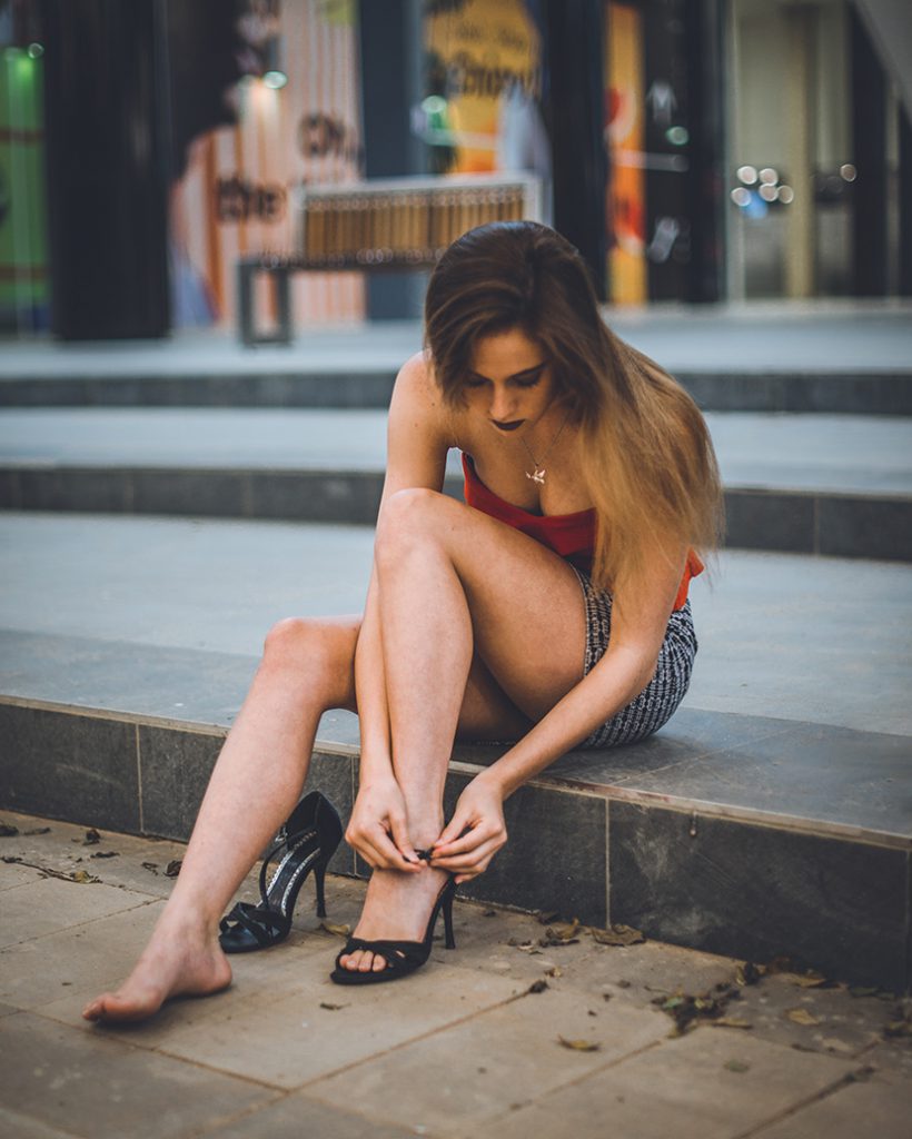 坐在街边石阶上系高跟鞋的性感红衣女