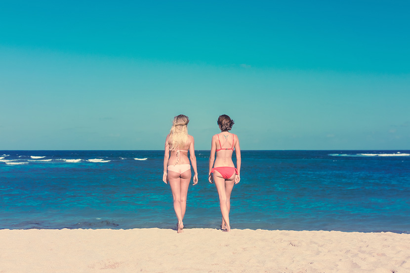 在蔚蓝的大海边漫步的两个泳装女人