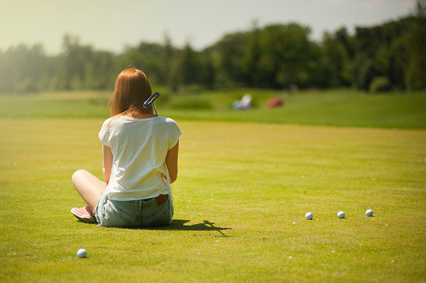坐在高尔夫球场上的白T恤少女