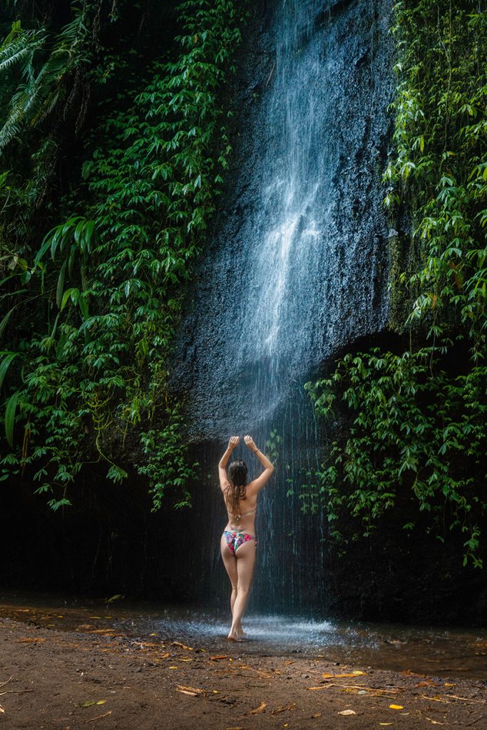 在深山小瀑布前冲澡的泳装性感女人