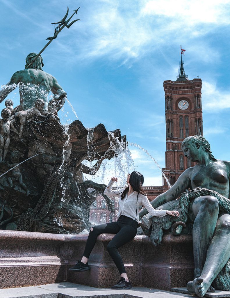 坐在海王波塞冬喷泉雕像前的少女
