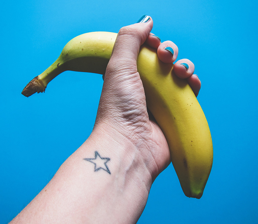 女人手握一根带皮的香蕉