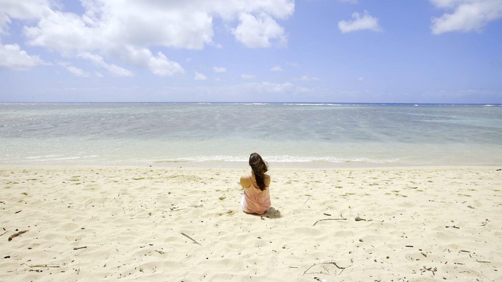 在海边白色沙滩上坐着的女人短视频素材