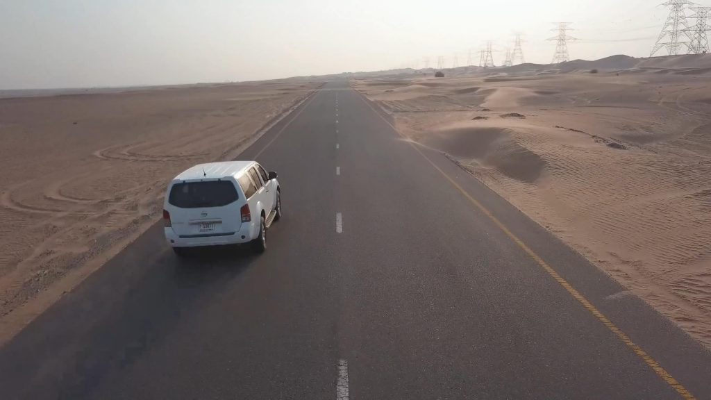 从沙漠荒野公路上呼啸而过的小面包车短视频素材