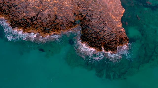海边红色礁石边的浪花点点航拍正射短视频素材【4K】