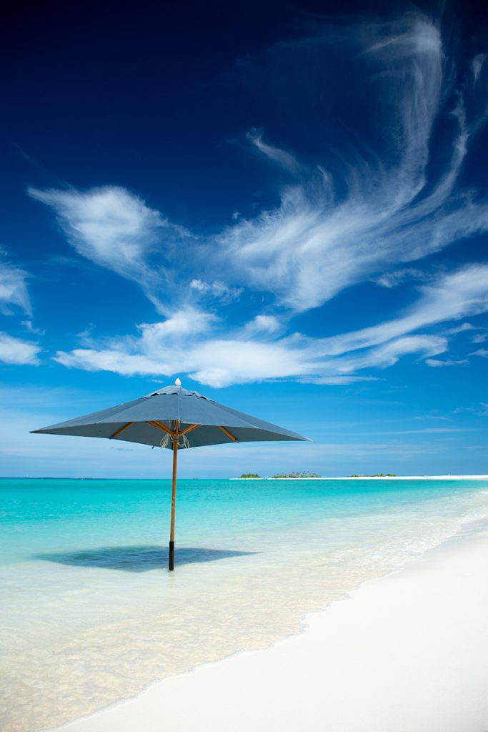 蓝天白云下的白色沙滩遮阳伞