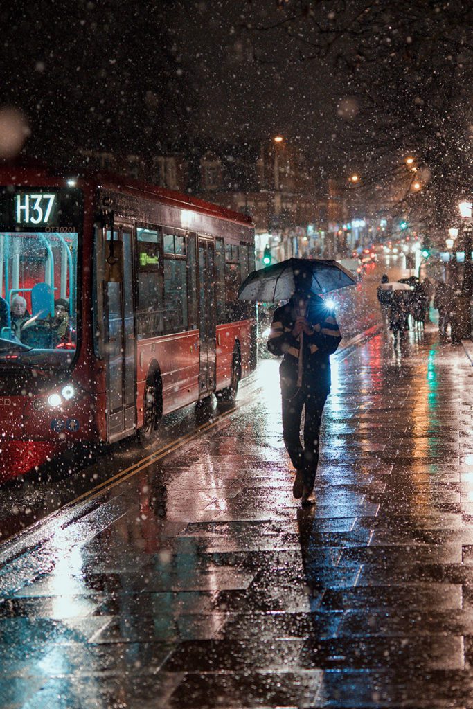 下雨天的都市街道公交车打伞的男人