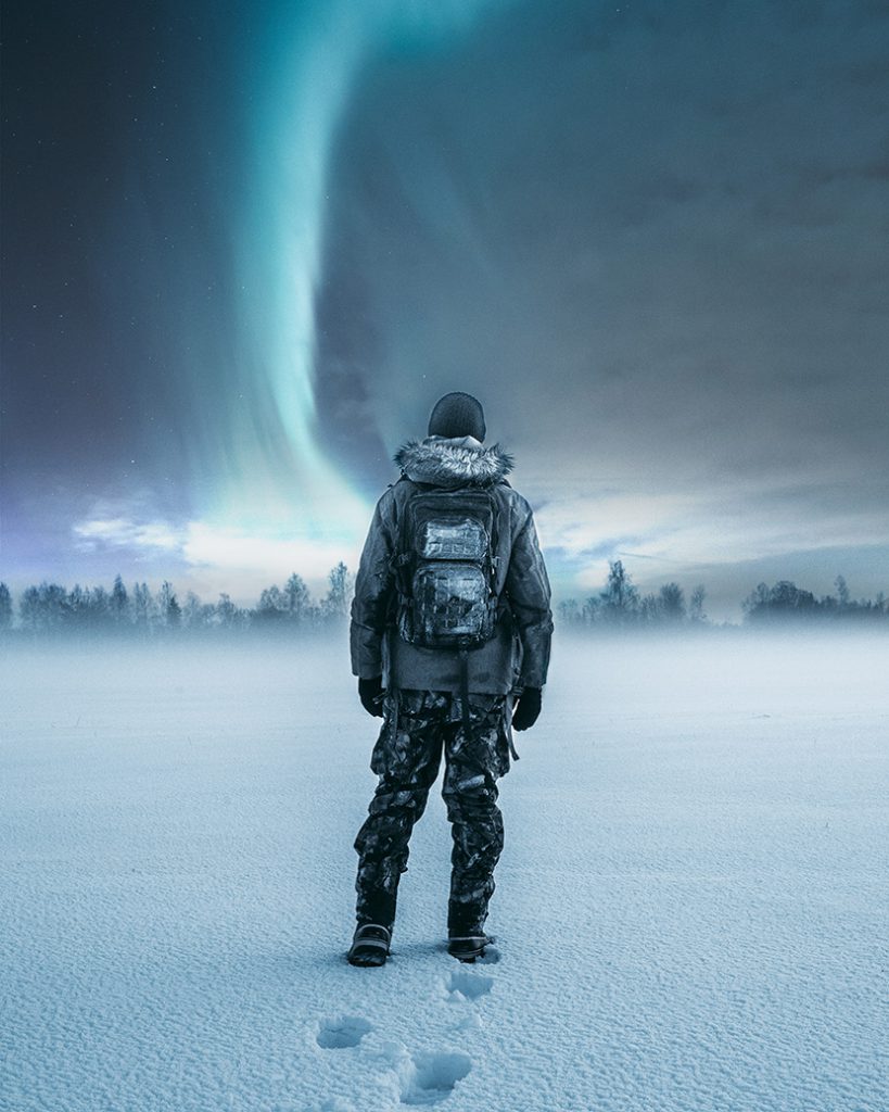 站在雪地上的户外探险者在看极光
