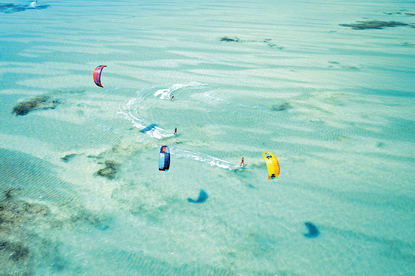 在海边玩风筝冲浪的人们