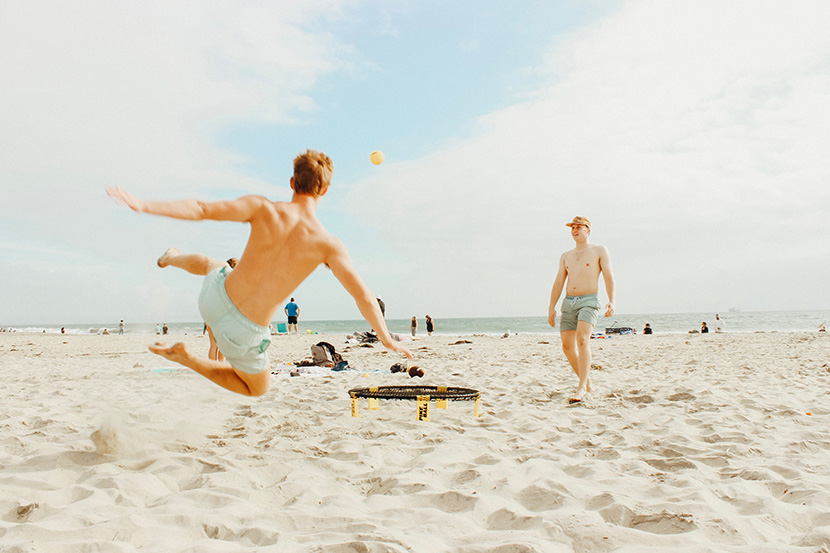玩沙滩足球的两个男人