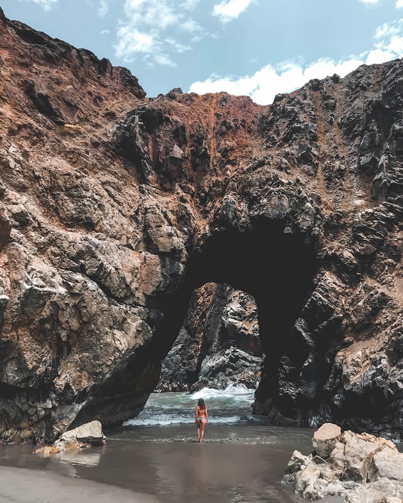 海边礁石洞窟下的泳装女人