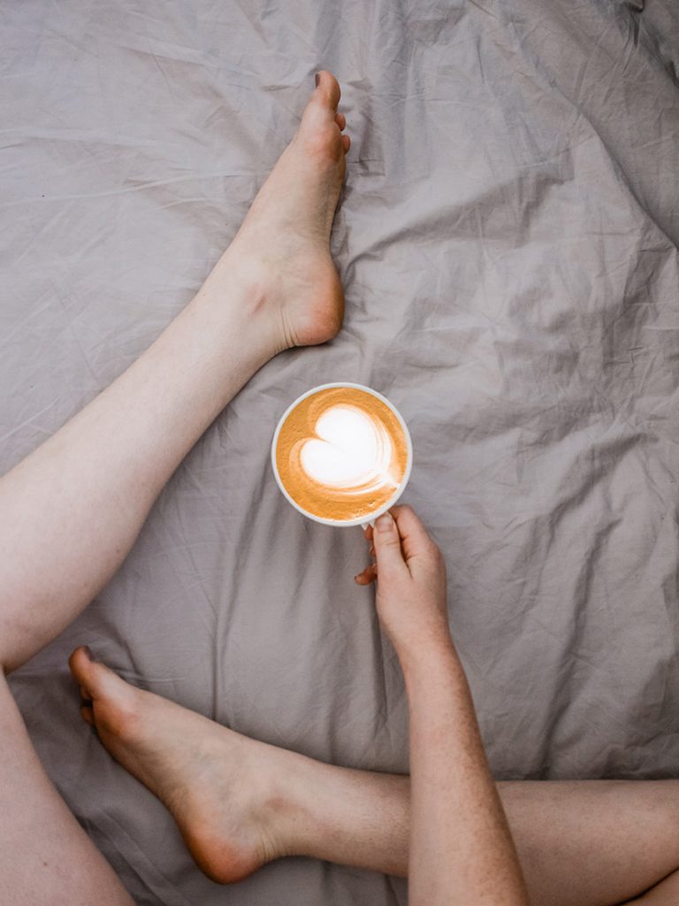坐在床上喝咖啡的女人