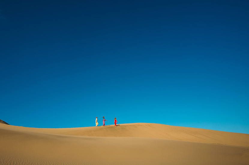 蓝天下沙漠上的三个妇人