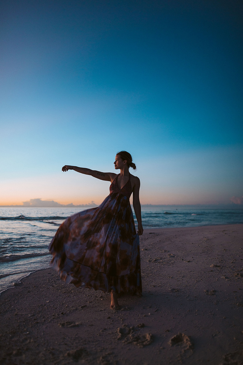 蓝色天空下沙滩上的连衣裙少女