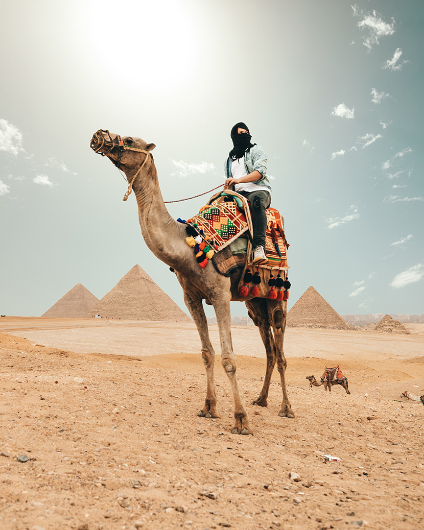 骑着骆驼在埃及金字塔前旅游的妇人