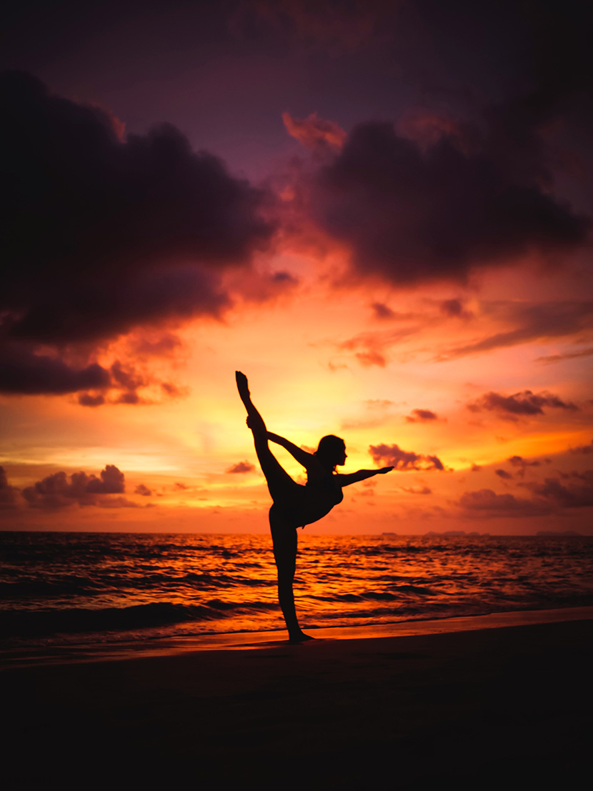 夕阳下在海边练瑜伽的女孩