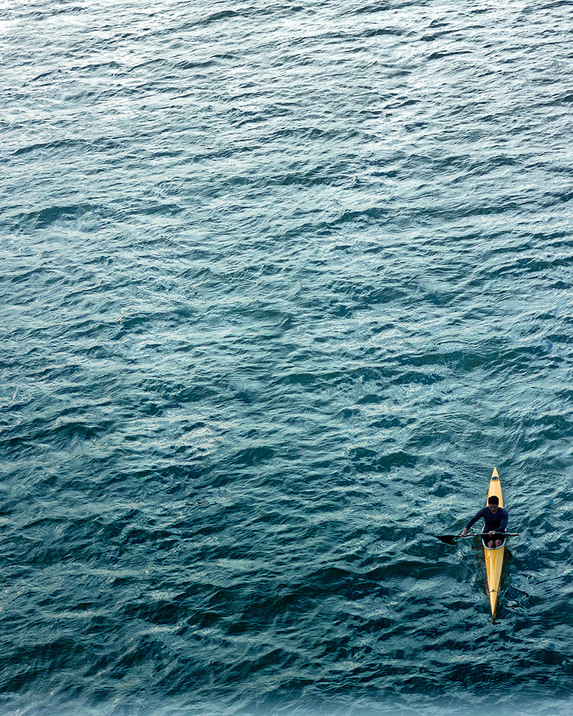 在辽阔的海面上玩皮划艇的男人