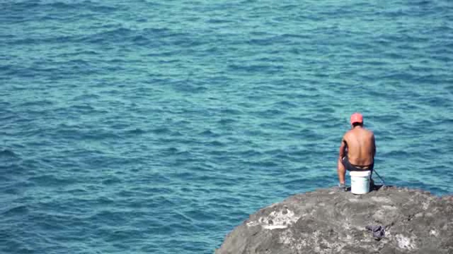在海边礁石上钓鱼的男人短视频素材